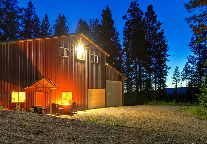 Metal buildings and roofing supplier in Livingston, LA Walker Metals. Image of large metal house barn lit up at night.