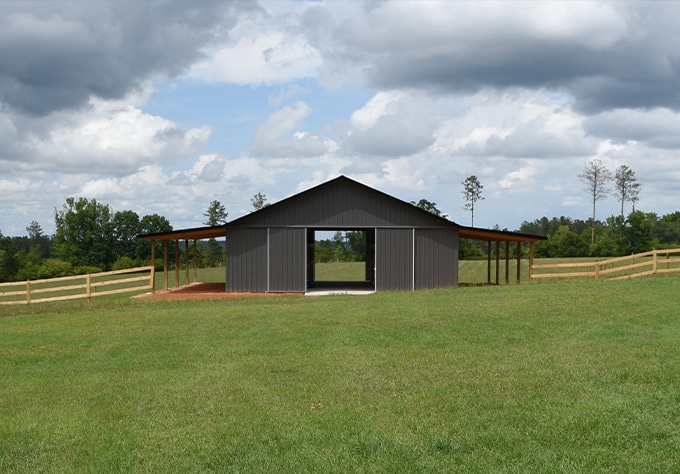 Metal buildings and roofing supplier in Greenwell, LA Walker Metals. Image of post frame metal horse barn in farm field.