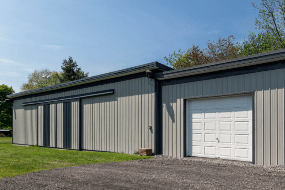 Metal building in a rural setting featuring sliding barn doors and a white roll-up garage door, constructed by Walker Metals doing metal building in Baton Rouge, LA.