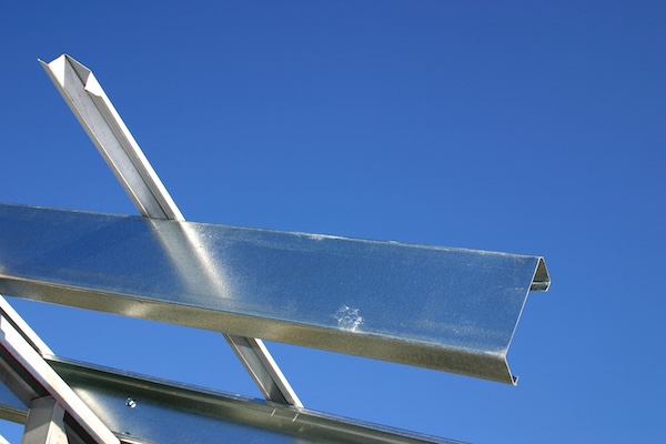 closeup of steel roof joist against a powder-blue sky showing purlin sizes and shapes