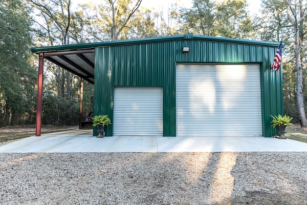pole barn carport in a sunny gravel yard against trees
